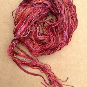 May include: A bundle of red, pink, and silver embroidery floss with a long tassel.