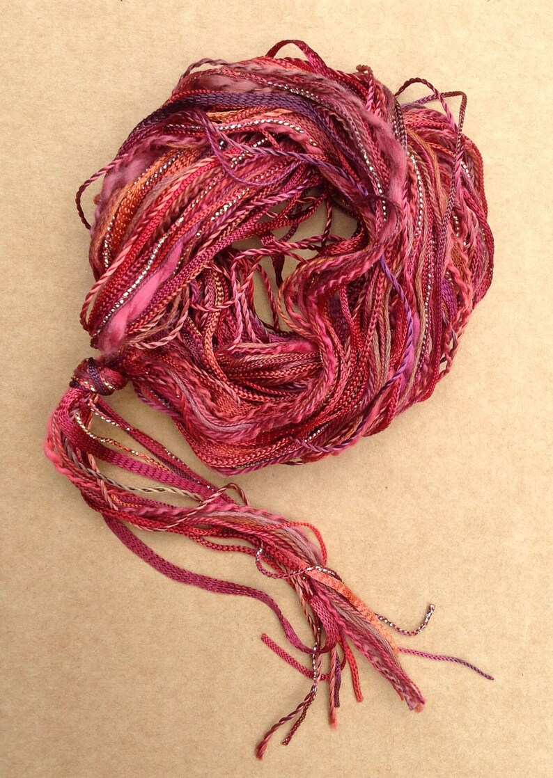 May include: A bundle of red, pink, and silver embroidery floss with a long tassel.