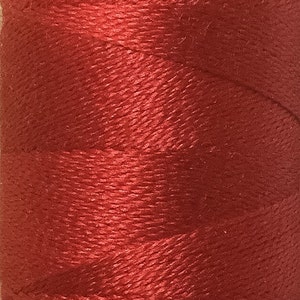 Może przedstawiać: Szpula czerwonej nici.