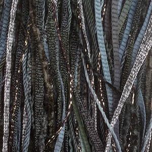 Puede incluir: Primer plano de una variedad de hebras de hilo en tonos de verde, azul y negro. El hilo está dispuesto en un patrón aleatorio, creando una textura y una visualización visualmente atractiva.
