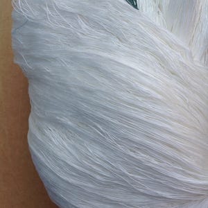 May include: A close-up of a bundle of white yarn. The yarn is soft and fluffy, and it is perfect for knitting or crocheting.
