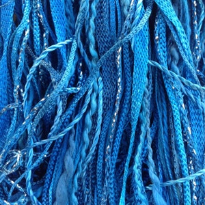 May include: A close-up of a bundle of blue and silver yarn. The yarn is soft and fluffy, and it is perfect for knitting or crocheting.