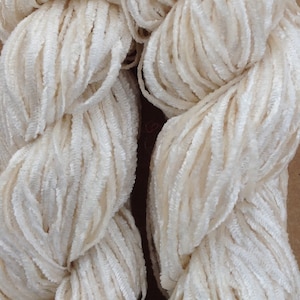 Op de afbeelding: Twee bollen witte garen met een pluche textuur.