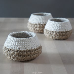 May include: Three crocheted baskets with a white top and a brown bottom. The baskets are made of natural fibers and have a rustic look.