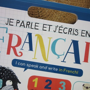 K&ouml;nnte beinhalten: Ein bunter Buchumschlag mit dem Titel "JE PARLE ET J'&Eacute;CRIS EN FRANCAIS" und dem Text "I can speak and write in French!" Der Umschlag zeigt eine Comicfigur mit gro&szlig;en Augen und einem blau-wei&szlig; gestreiften Schal.