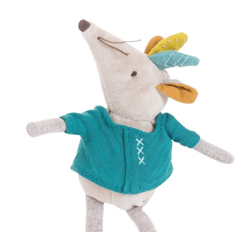 May include: A gray plush mouse toy with a teal blue shirt and colorful feathers on its head. The shirt has white stitching in the shape of an 'X'.