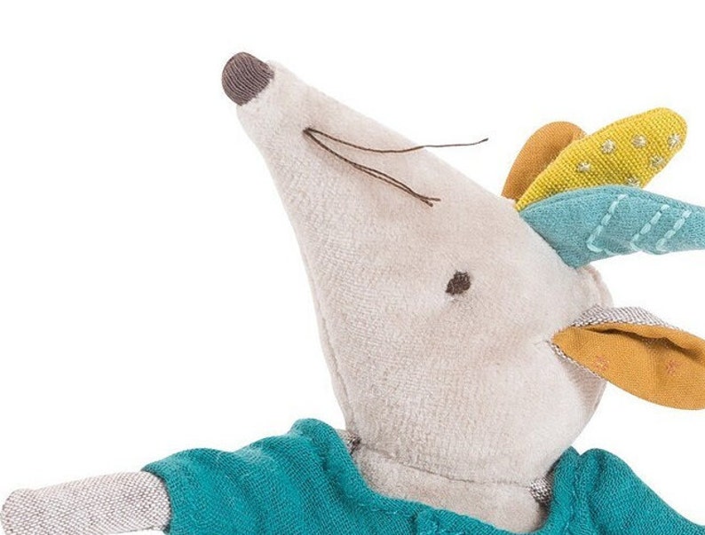 May include: A plush gray mouse toy with a blue and yellow patterned head. The mouse is wearing a teal blue shirt.