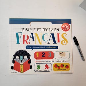 K&ouml;nnte beinhalten: Ein farbenfrohes Trockenl&ouml;schboard mit dem Text "Je parle et j'&eacute;cris en Fran&ccedil;ais" und "I can speak and write in French!" Das Board zeigt ein Cartoon-Monster, das ein Buch liest, die Zahlen 1-3, einen Welpen, einen Frosch, ein Puzzle-Teil und Erdbeeren. Das Board ist dazu gedacht, Kindern beim Franz&ouml;sischlernen zu helfen.