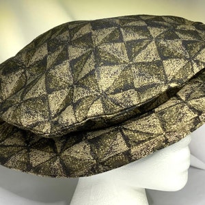 May include: A brown and gold patterned newsboy cap with a geometric design.
