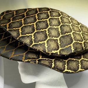 May include: A black and gold patterned newsboy cap with a geometric design.