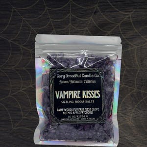 May include: A clear, iridescent bag filled with dark purple room salts. The label reads "VAMPIRE KISSES" and lists scent notes. The bag is from Gory Dreadful Candle Co., Autumn/Halloween Collection, and contains 425.24 g of product.