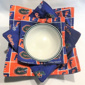 May include: Set of four blue and orange fabric bowl cozies with an alligator logo and the text "Florida Gators".