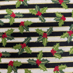 May include: Black and white striped fabric with a repeating pattern of green holly leaves and red berries. The stripes are accented with gold thread.