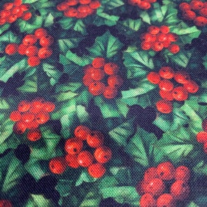 May include: A green fabric with a repeating pattern of red berries and green leaves. The fabric has a textured surface.