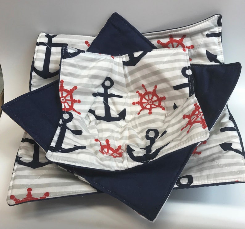 May include: Set of three navy blue and white striped pot holders with anchors and red steering wheels. The pot holders are quilted and have a layer of navy blue fabric on the back.
