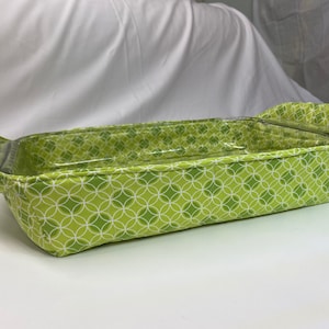 May include: Green and white patterned fabric casserole dish carrier with a clear glass baking dish inside.