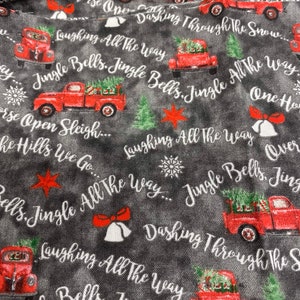 May include: Red pickup trucks with Christmas trees in the back drive through a snowy landscape. The trucks are surrounded by the words "Jingle Bells, Jingle All The Way" and "Dashing Through The Snow".