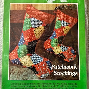 May include: A package featuring a patchwork stocking pattern. The image shows two stockings with a patchwork design in red, green, blue, and yellow. The text reads "Patchwork Stockings" and includes finished sizes of approximately 14" and 19".