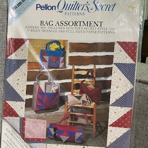 May include: A vintage quilting pattern booklet featuring a bag assortment. The cover shows four different bags made with patchwork fabric in red, blue, and white. The title of the pattern is "Quilter's Secret" and the pattern number is #102. The pattern includes quilter's secret style 704B, 4" right triangle and full-sized paper patterns.