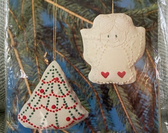 May include: A craft kit for making two candlewicking ornaments. The kit includes white cotton muslin fabric, colored candlewicking yarn, gold metallic thread, a needle, and instructions. The ornaments are a Christmas tree and an angel.