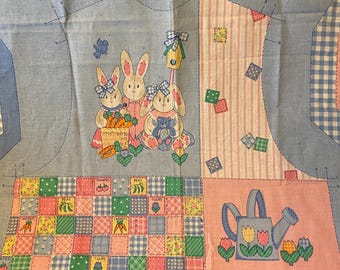 May include: A blue and pink fabric panel with a patchwork design featuring bunnies, a birdhouse, and a watering can. The fabric also includes instructions for making a vest with the text "Leave Open" and "Sketch A" and "Sketch B".