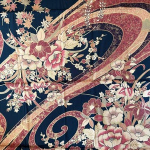 May include: A dark navy fabric with a floral pattern featuring large pink and cream-colored flowers, along with smaller blossoms and leaves. The design includes flowing, ribbon-like shapes in shades of burgundy, gold, and cream.