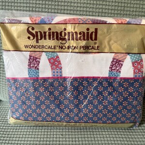 May include: A packaged Springmaid Wondercale no-iron percale king flat sheet. The sheet has a patchwork design in red, blue, and purple, and a blue floral pattern. The packaging is gold with the brand name in large letters.