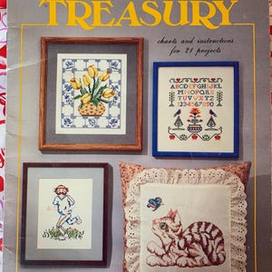 May include: A book titled "Cross Stitch Treasury" with charts and instructions for 21 projects. The cover features four framed cross stitch designs: a bouquet of yellow tulips, an alphabet, a running figure, and a cat with a butterfly.
