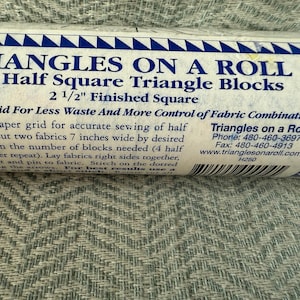 May include: A roll of paper labeled "TRIANGLES ON A ROLL" with text indicating 700 half-square triangle blocks, 2 1/2" finished square. The roll has a blue and white border and includes instructions for fabric sewing.
