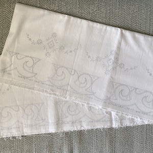 May include: Three white fabric panels with embroidered floral and geometric designs. The panels are layered on top of each other, with the top panel being the largest. The embroidery is in a light gray color.