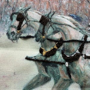 May include: Embroidered artwork featuring two horses in a winter scene. The horses are depicted in shades of gray and teal, with black and gold embroidered details for the harnesses. The background shows a blurred winter landscape.
