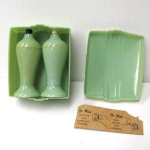 May include: Vintage green salt and pepper shakers in a matching green plastic case. The shakers are vase-shaped with black and beige stoppers. The case has a lid and a small instruction card.