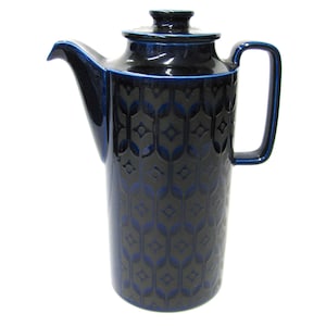 May include: A tall, dark blue ceramic coffee pot with a matching lid and handle. The pot features a repeating pattern of stylized leaves in a lighter shade of blue. The spout is curved, and the handle is rectangular.