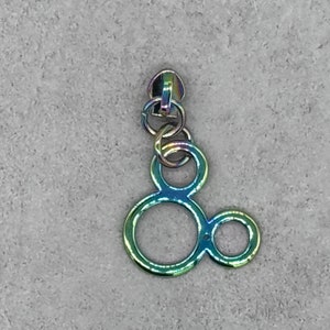 Może przedstawiać: Suwak do zamka błyskawicznego w kolorze tęczy z wzorem głowy Myszki Miki. Suwak jest wykonany z metalu i ma łańcuszek przymocowany do górnej części.