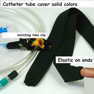 May include: Dark green catheter tube cover with elastic ends. Includes a matching tube clip with a sunflower design. The text on the image reads "Catheter tube cover solid colors", "matching tube clip", and "Elastic on ends".