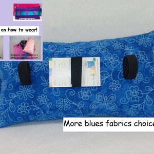 May include: A blue floral patterned pillow with black straps and a white label. The pillow has a rectangular shape and is made of fabric. The image includes examples of how to wear the pillow. Text on the image reads "More blues fabrics choices."