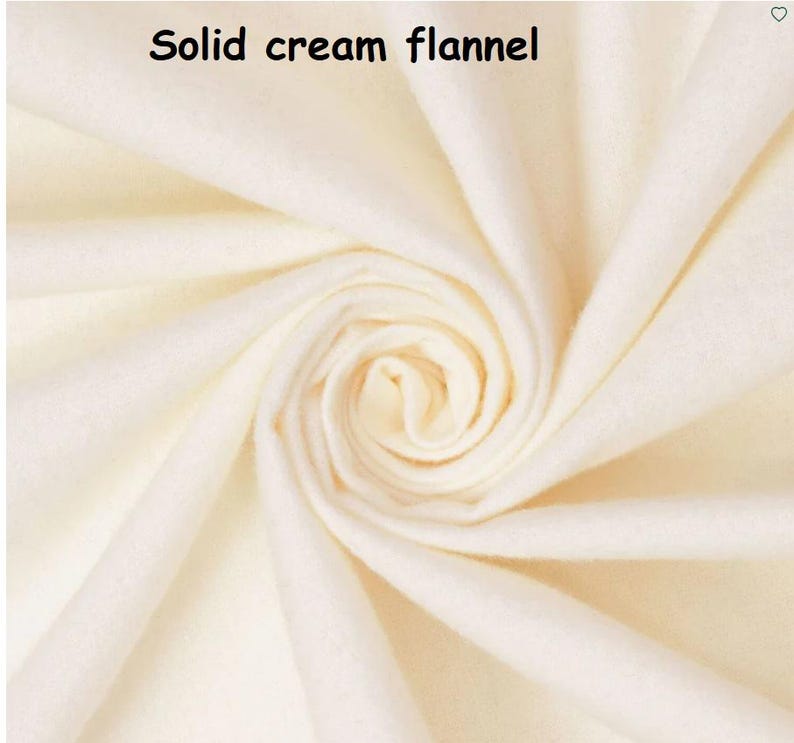 Puede incluir: Primer plano de tela de franela color crema, doblada para mostrar la textura y profundidad del material. Las palabras "Solid cream flannel" est&aacute;n impresas en la parte superior. La tela parece suave y acogedora, ideal para proyectos de ropa o decoraci&oacute;n del hogar.