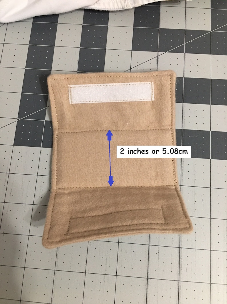May include: A rectangular tan felt wrap featuring a white hook-and-loop fastener strip at the top and a matching strip at the bottom. A blue arrow graphic indicates a central section height of 5.08 cm or 2 inches between the stitched horizontal lines.