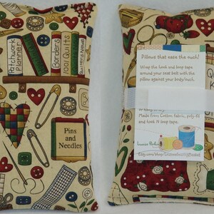May include: Two beige fabric pillows with a quilting theme. The pillows are filled with poly-fil and have hook and loop tape for attaching to a seat belt. The pillows are decorated with a variety of quilting-themed images, including sewing needles, pins, scissors, buttons, and fabric scraps. The pillows are made by Louise Perkin and are available on Etsy.