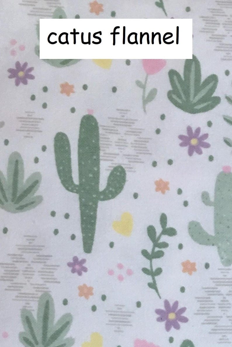 Puede incluir: Una tela de franela blanca con un patr&oacute;n repetitivo de cactus verdes, flores moradas, corazones amarillos y peque&ntilde;as flores naranjas. El texto "catus flannel" est&aacute; impreso en letras negras en la parte superior central del patr&oacute;n.