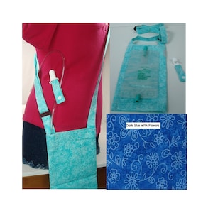 May include: A light blue fabric pouch with a white floral pattern designed to hold a medical drainage bag. The pouch features an adjustable shoulder strap and a small matching fabric tab with a snap closure to secure the drainage tube.