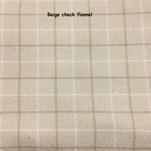 May include: A beige flannel fabric featuring a light brown check pattern. The textile has a soft, brushed texture with a grid design composed of thin, intersecting lines. The text "Beige check flannel" is printed in black at the top centre.