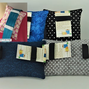 May include: Four different fabric neck pillows with black straps and tags that say "Pillow that made the mask!" and "Fiber that felt the heat!" The pillows are in blue floral, black and white polka dot, gray and white polka dot, and blue floral patterns.