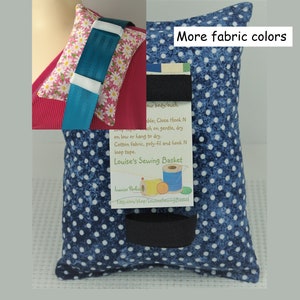 May include: A blue and white polka dot fabric sewing basket with a black hook and loop tape closure. The basket is filled with sewing supplies, including thread, needles, and a small pair of scissors. The text "Louise's Sewing Basket" is printed on a tag attached to the basket.