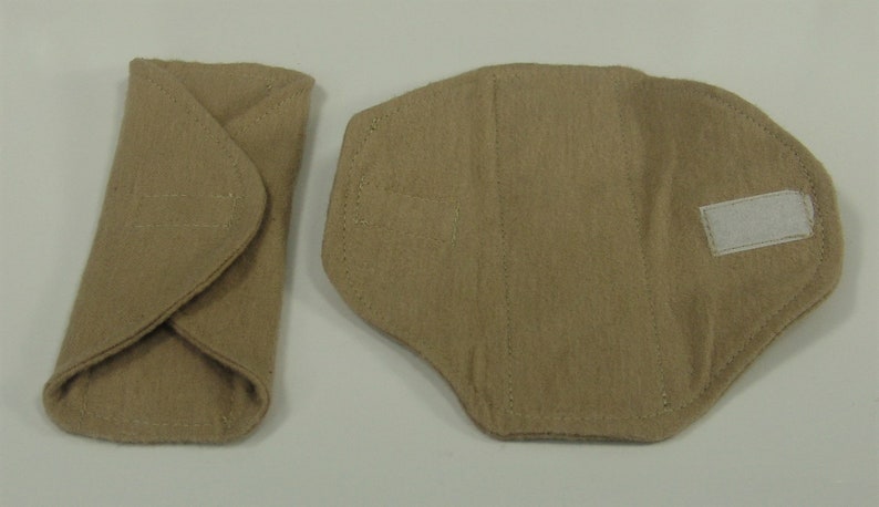 Puede incluir: Dos compresas menstruales de tela beige. Una est&aacute; doblada y cerrada, la otra est&aacute; abierta con un cierre de velcro blanco. Ambas est&aacute;n hechas de un material suave y absorbente, dise&ntilde;adas para la comodidad y la protecci&oacute;n.