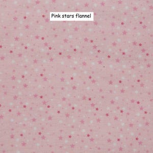 Puede incluir: Tela de franela rosa claro con un estampado de peque&ntilde;as estrellas en tonos rosas y blancos. El texto "Pink stars flannel" se muestra en un rect&aacute;ngulo blanco.