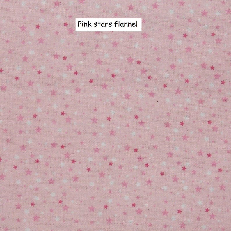 Puede incluir: Tela de franela rosa claro con un estampado de peque&ntilde;as estrellas en tonos rosas y blancos. El texto "Pink stars flannel" se muestra en un rect&aacute;ngulo blanco.
