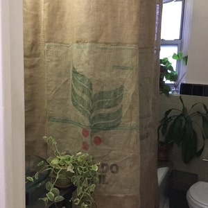 May include: A bathroom shower curtain made from repurposed burlap coffee sacks. The curtain features a green leaf design and the text "HYDROCARBON" and "DO IL".
