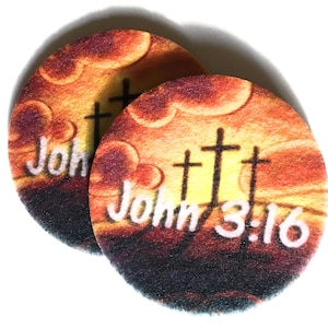 May include: Two round coasters with a sunset background and three crosses. The text "John 3:16" is printed on the coasters.