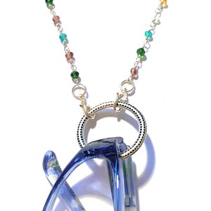 May include: A silver chain with colorful beads and a silver ring for holding glasses. The chain is designed to be worn around the neck and the ring is used to hold glasses securely.